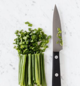 Three-riveted knife cutting fresh green onion
